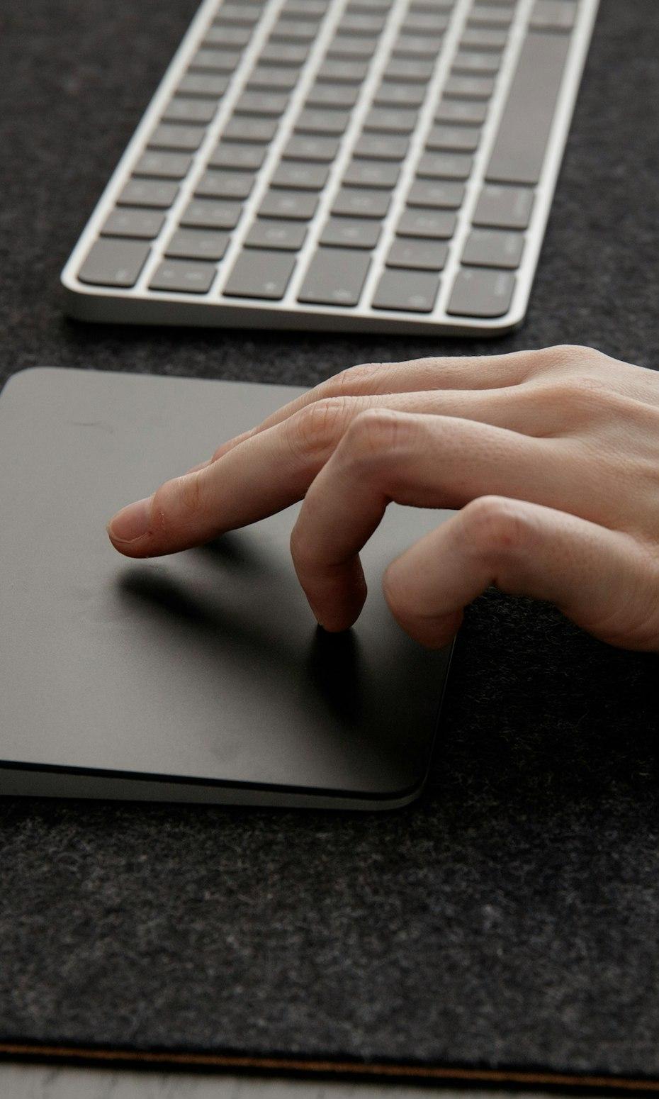 A hand pausing over a trackpad before clicking